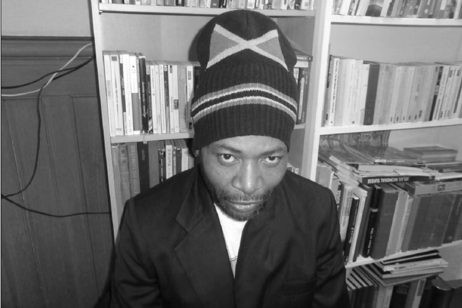 Wesley boasting his Jamaican flag beanie while sitting in Espace Solidaire Paquis library (Photography : Delphine Luchetta)
